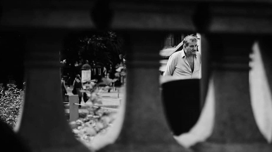 Street — stari moški skozi ograjo